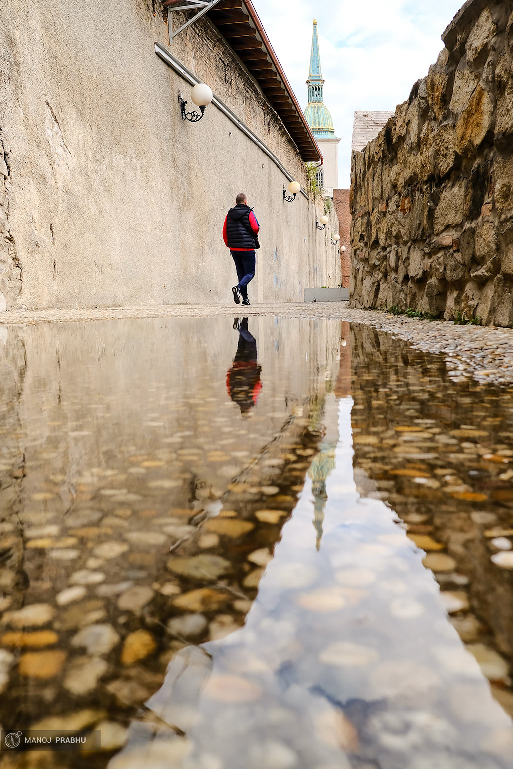 Reflection of a man walking in a pool of water in Bratislava. (Shot on Fujifilm X-Pro2 using Kodak Ektar 100 film simulation recipe)
