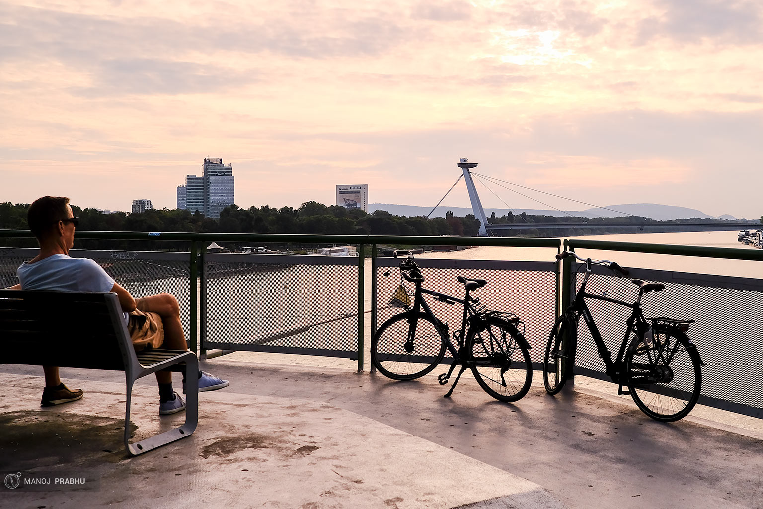 A man sitting next to his bicycle near a river bank watching a sunset. (Shot on Fujifilm X-Pro2 using Kodak Ektar 100 film simulation recipe)